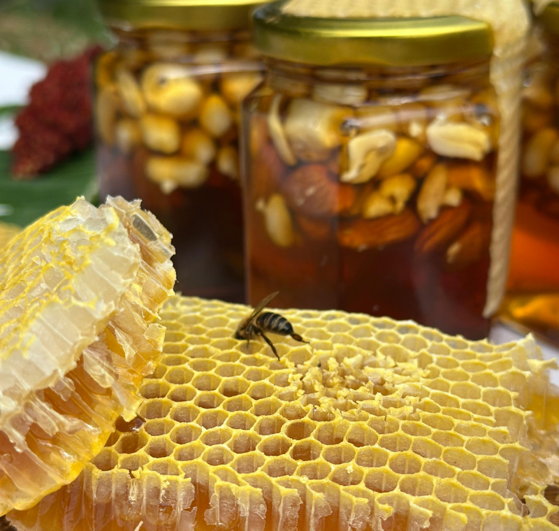 Glass jar of raw organic honey with golden color and wooden dipper