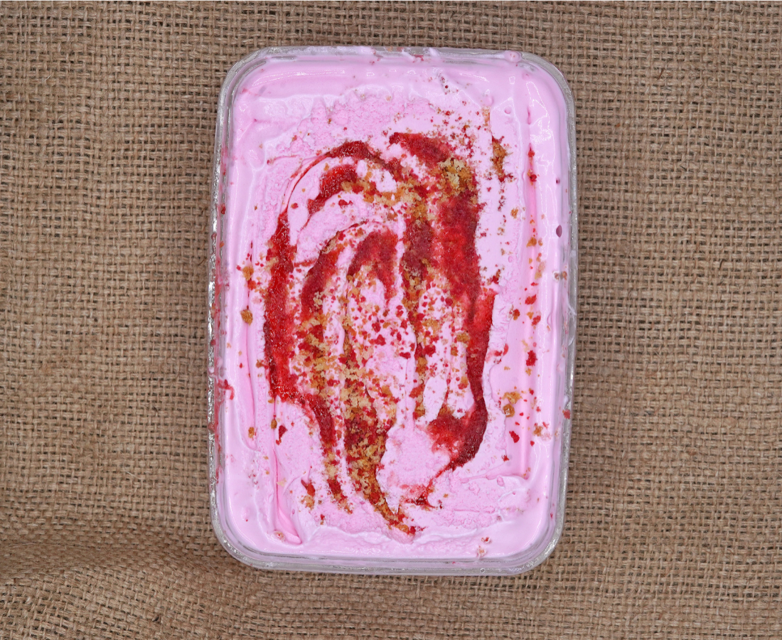 Slice of creamy strawberry cheesecake topped with fresh strawberries on a white plate